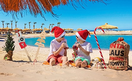 Дети в новогодних шапках играют на пляже египетского курорта