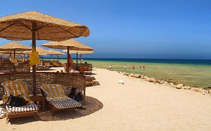 Тихий пляж бухты Макади с пальмами и шезлонгами для отдыха